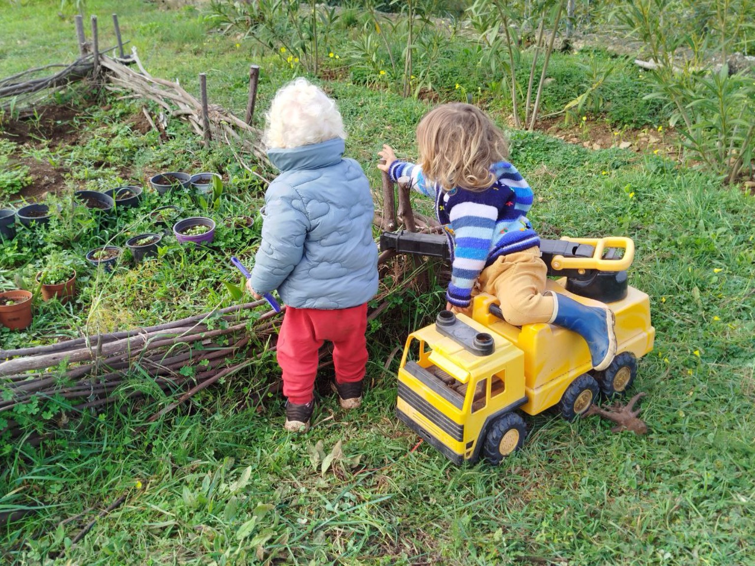 Dos niños de espaldas construyendo con ramas