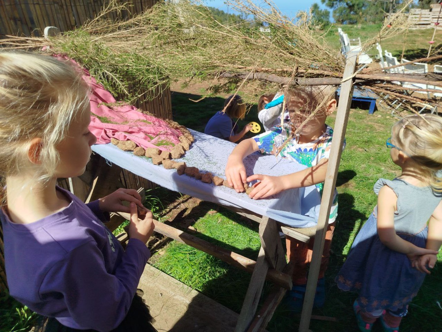 Niños de espaldas creando con materiales naturales al aire libre