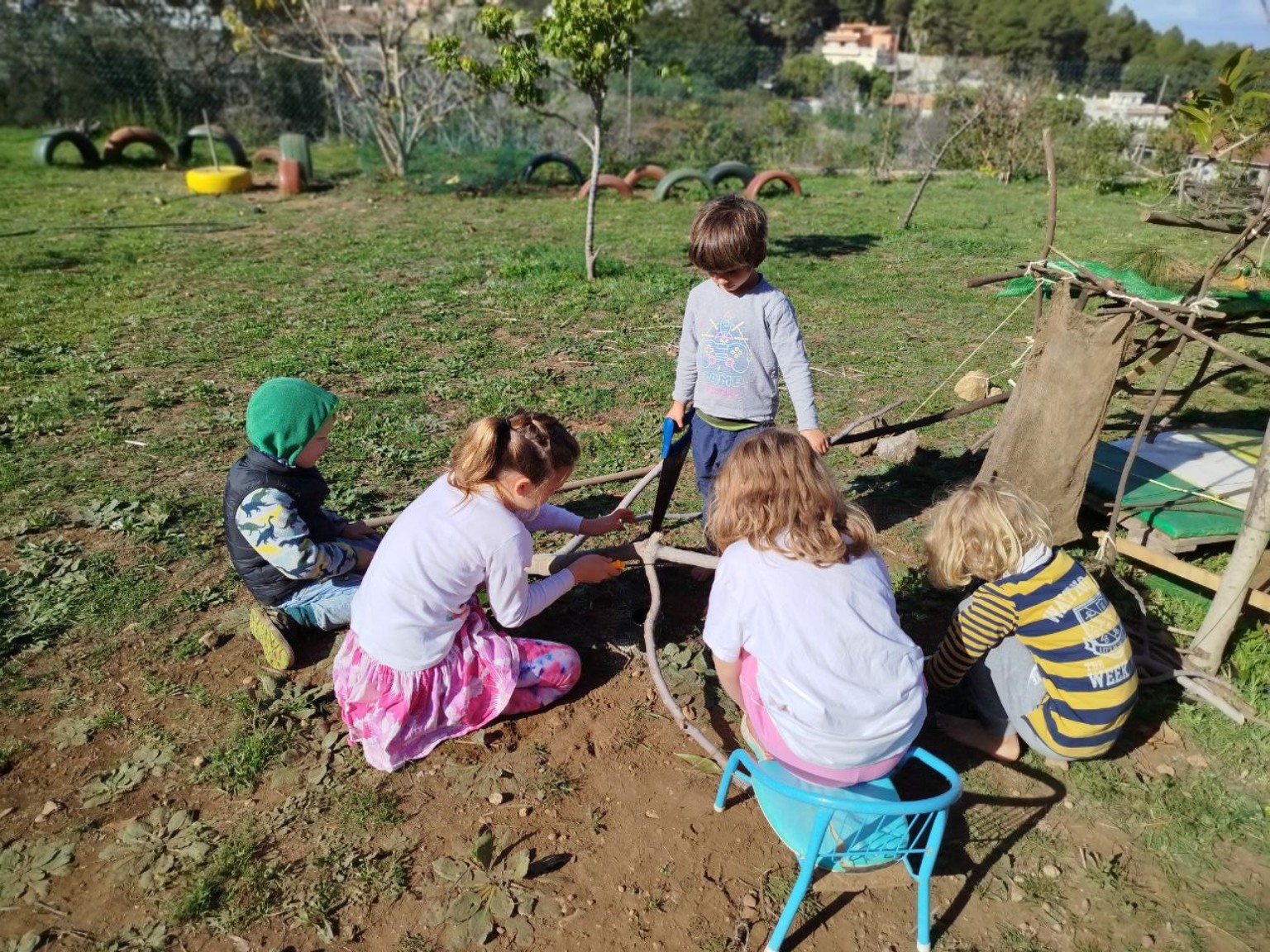 Grupo infantil visto desde atrás compartiendo una actividad con ramas